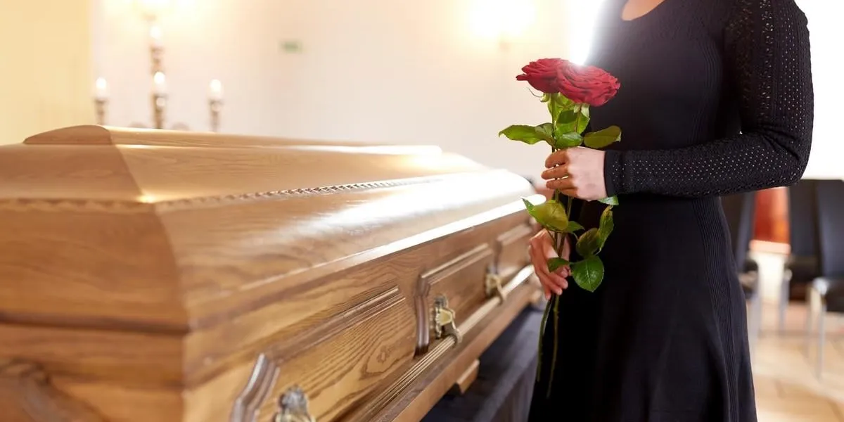 concept de personnes et de deuil - femme avec des roses rouges et cercueil à l'enterrement dans l'église