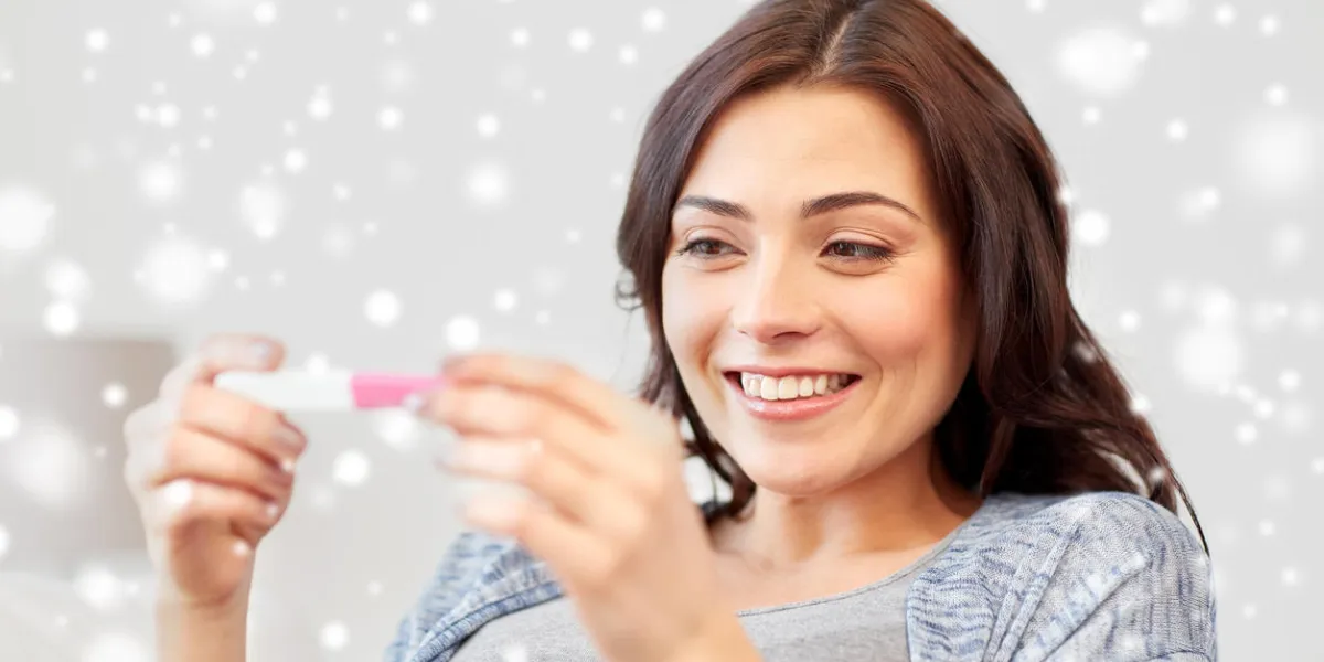 concept de fertilité, hiver, maternité et personnes - heureuse femme souriante regardant test de grossesse à la maison sur la neige