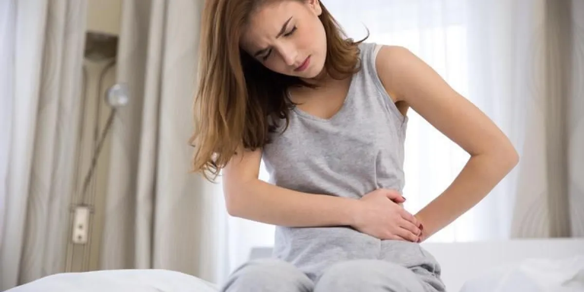 jeune femme assise sur le lit avec douleur