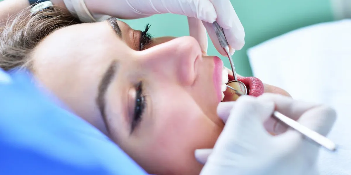 une jolie jeune femme avec un sourire blanc et lumineux allongé dans la chaise du dentiste ayant un bilan de santé