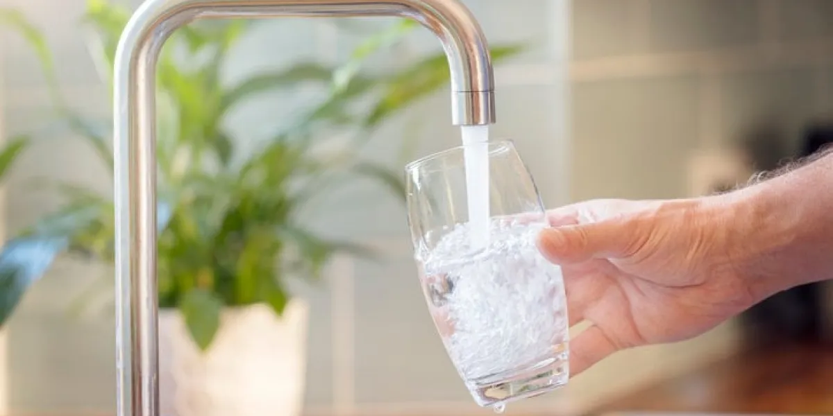 filling up a glass with clean drinking water from kitchen faucet