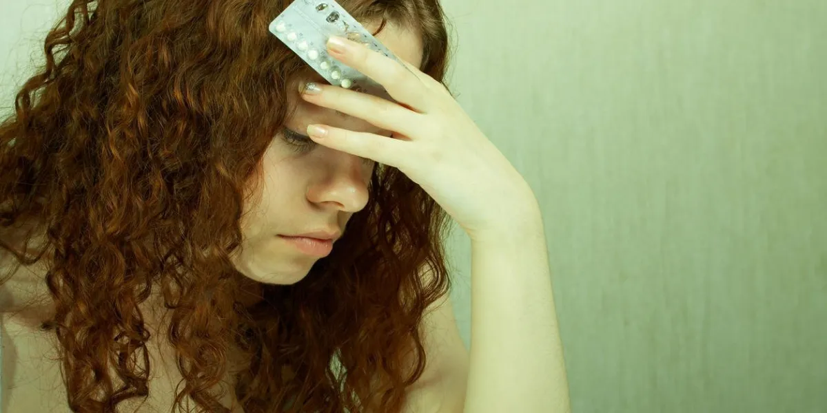 la fille dans la confusion tient des comprimés contraceptifs dans les mains