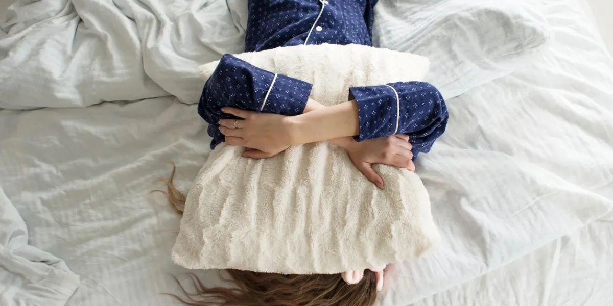 too lazy to get out of bed, a woman covers her face with a pillow