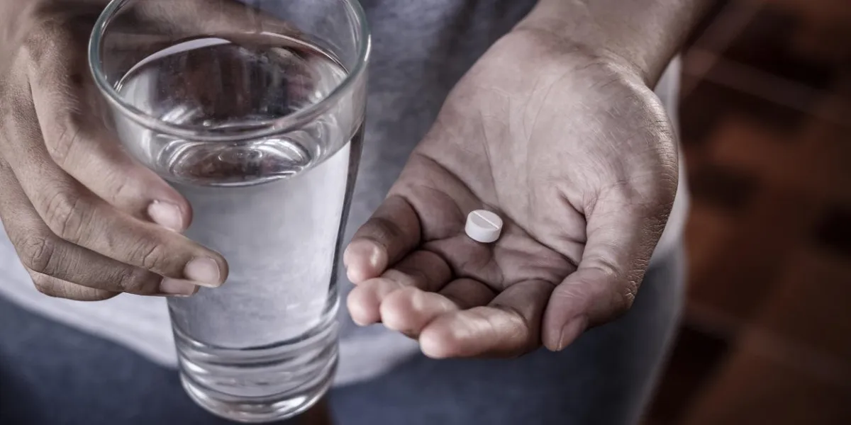 close up of girl holding paracetamol and glass of water