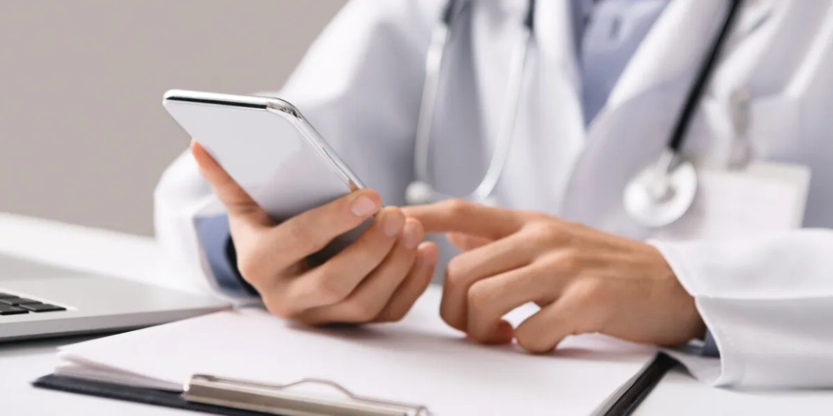 consultation online unrecognizable male doctor using smartphone at workplace, messaging with his patient, prescribing treatment