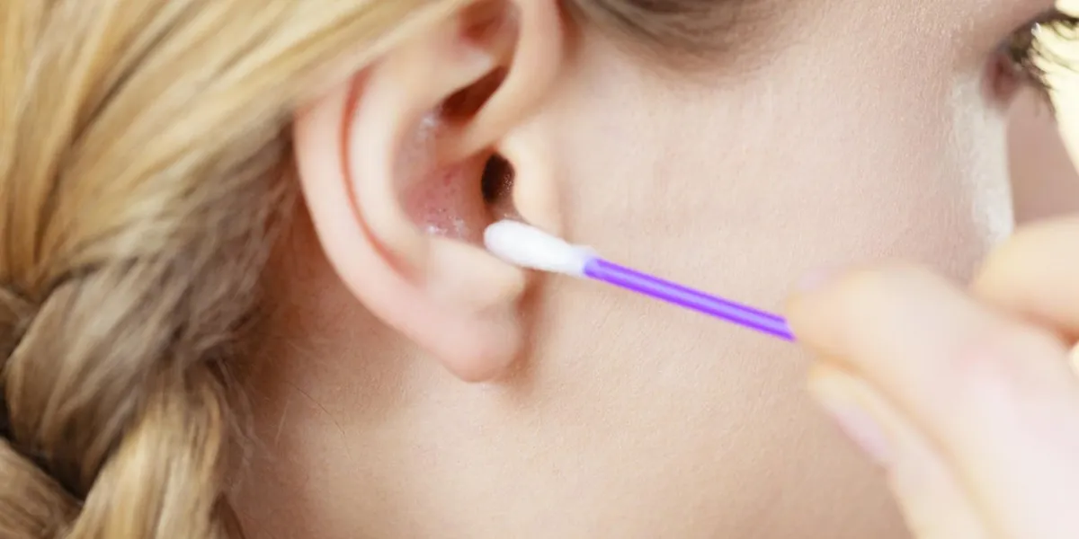 hygiene concept young woman cleaning ear with cotton swabs closeup