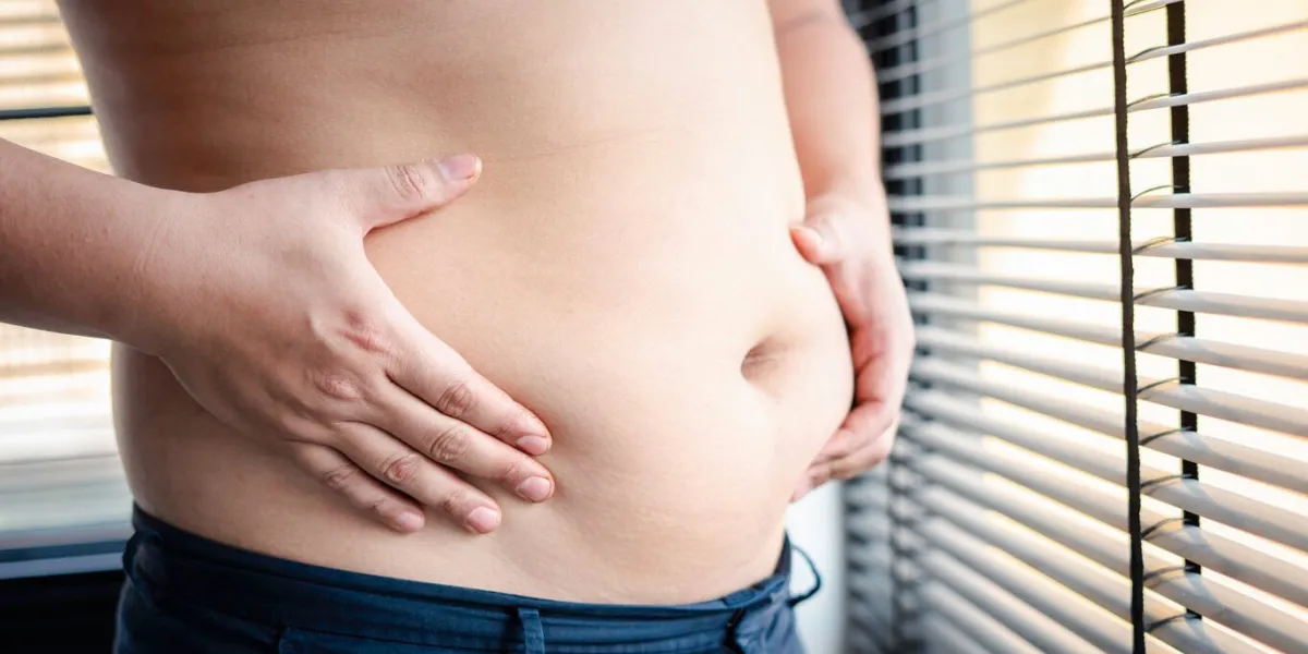 fat man holding his own belly thinking of starting to lose weight and diet before getting sick with excessive abdominal fat, belly fat concept and weight loss