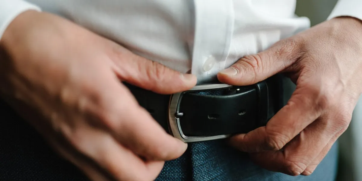 a man in pants and shirt buttoned a black leather trouser belt groom dress up a belt with a buckle businessman wear leather stylish belt close up