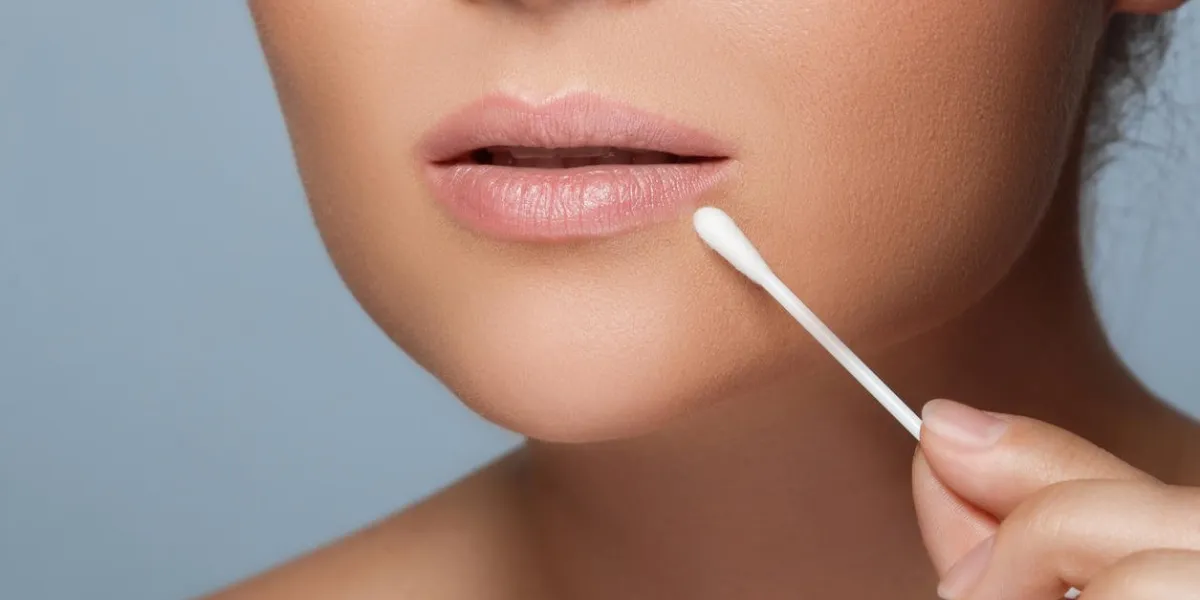 young woman with a cotton swab beside her lips