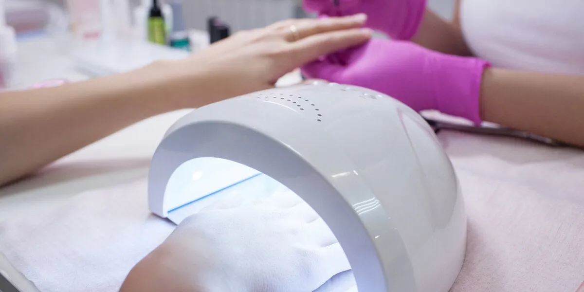 uv lamp gel polish manicure process salon procedure the master coats the client's nails with a varnish