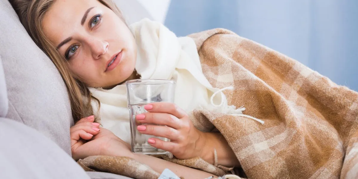 fille malade avec écharpe sur le cou, allongée sur le canapé, prendre des médicaments
