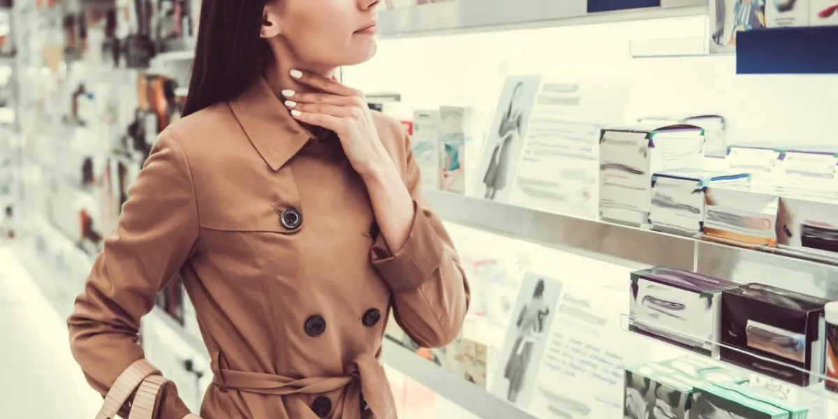 beautiful young woman is having a sore throat while searching for a medication at the pharmacy