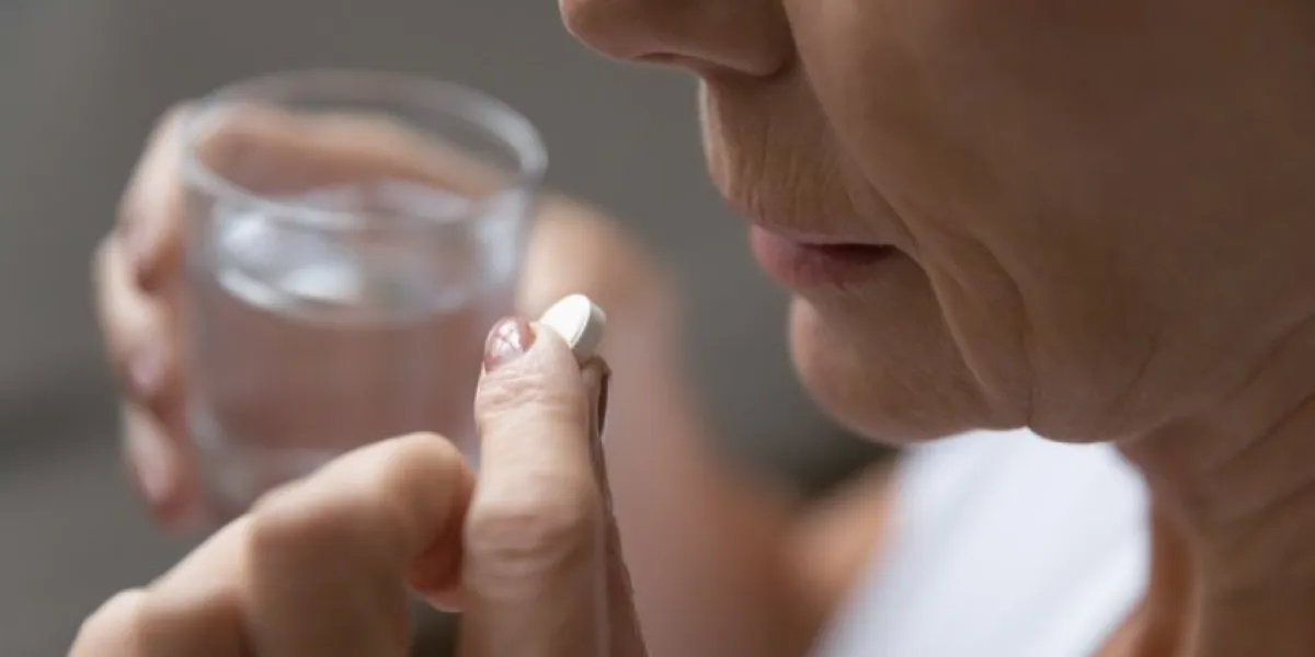 close up of mature sick woman having antibiotic aspirin pill suffering from headache or migraine, ill senior female take daily dose of vitamin or supplement, medications, elderly healthcare concept
