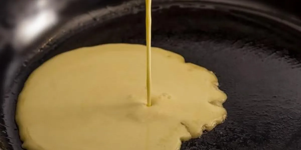 pâte à crêpes verser dans une poêle noire sur un poêle