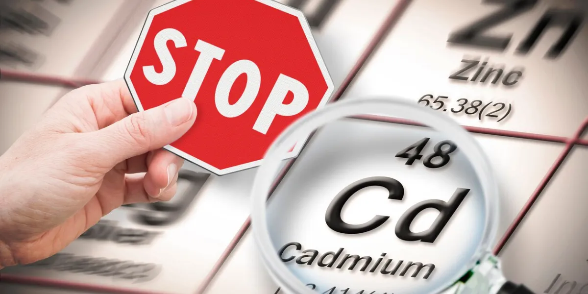stop heavy metals - concept image with hand holding a stop sign against a cadmium chemical element with the mendeleev periodic table seen through a magnifying glass