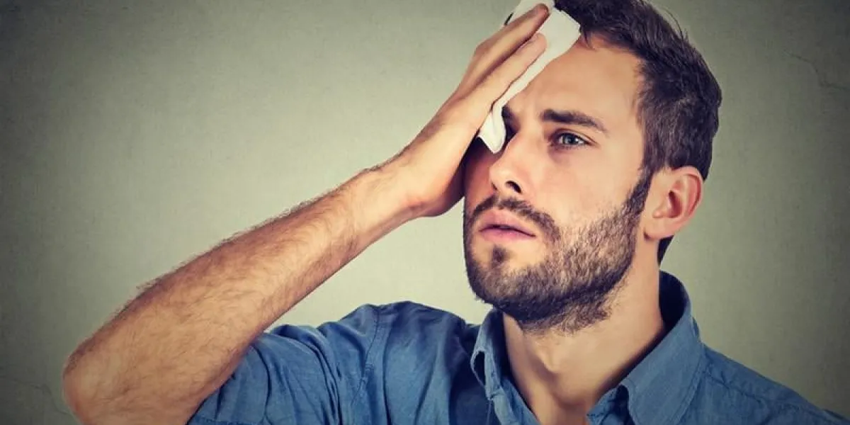 homme fatigué a souligné la transpiration ayant des maux de tête de fièvre isolé sur fond de mur gris homme inquiet des lingettes transpire sur son visage