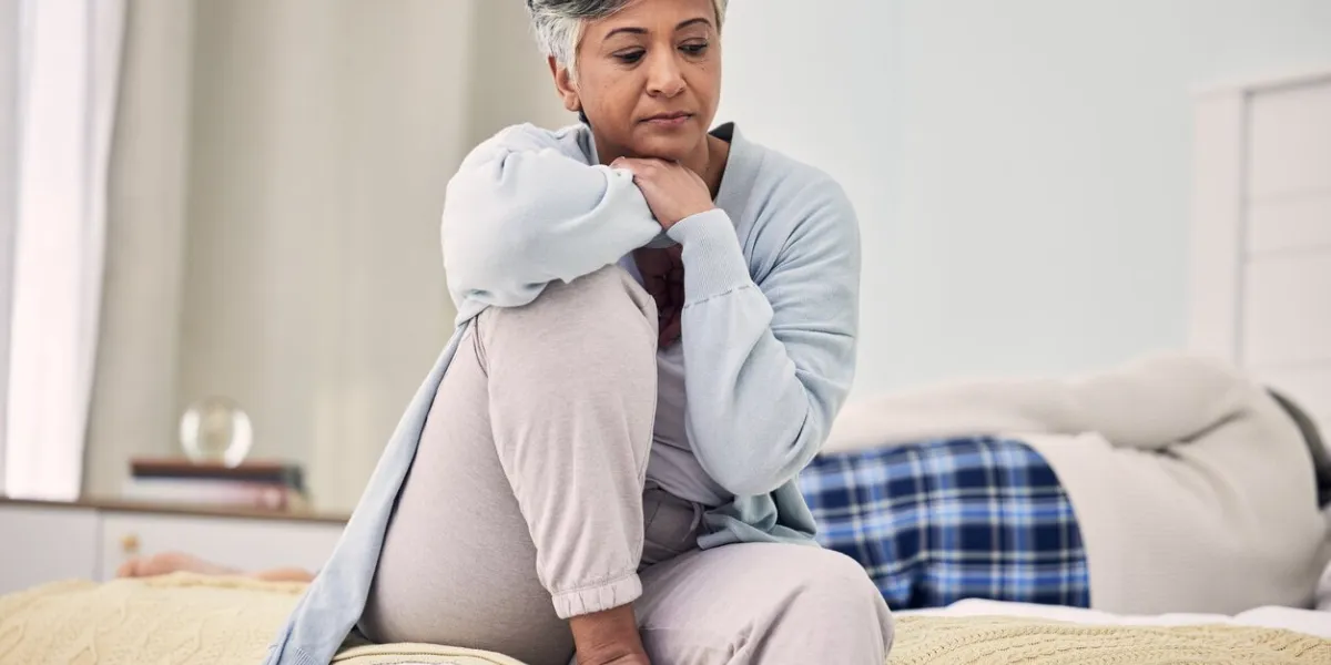 divorce, sad and senior woman with depression in bedroom or frustrated with problem or fear infidelity, marriage and fight with elderly female with stress in home or angry with partner or couple