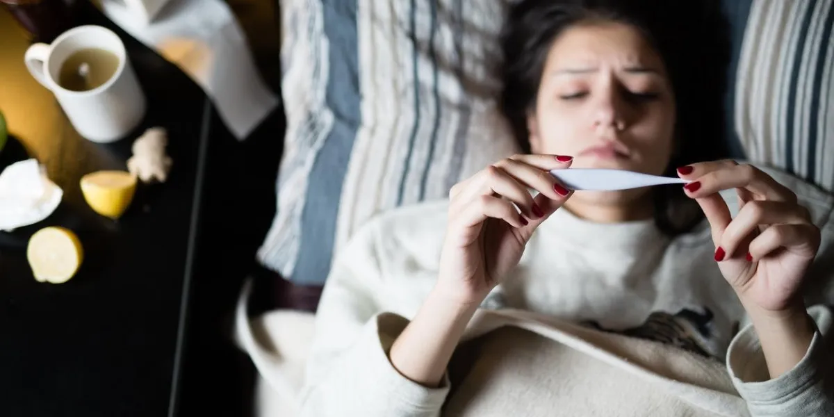 sick woman in bed,calling in sick,day off from workthermometer to check temperature for fevervitamins and hot tea in frontfluwoman caught coldvirussick woman laying in bed under wool blanket
