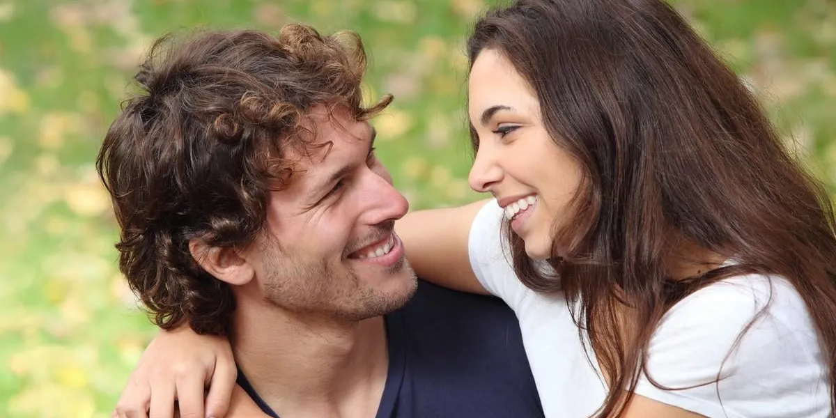 couple cuddling and flirting in a park with a green unfocused background