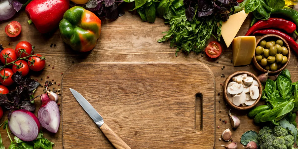 top view of cutting board, knife, fresh vegetables and herbs on wooden tabletop