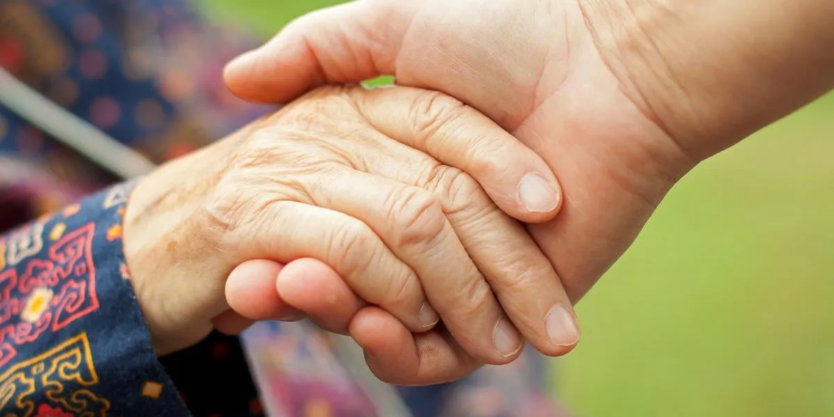 main de médecin tenant une main âgée froissée