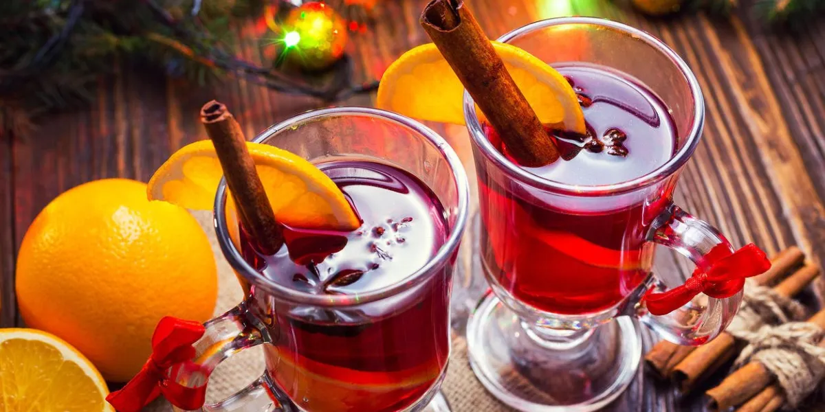 deux verres, tasse de boisson chaude rouge vin chaud sur fond en bois avec des épices de noël, tranche d'orange, gros plan vin de noël chaud branche de sapin de noël, lumières de noël