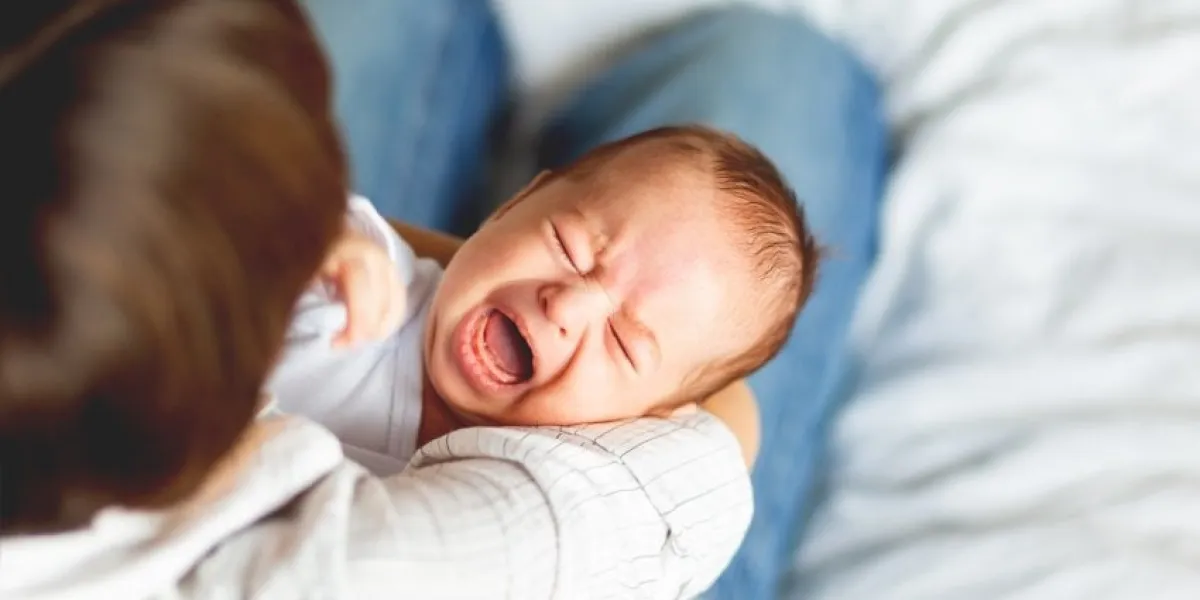 woman holding a crying child mother comforts her little son or daughter
