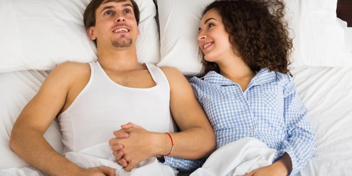 happy man and woman lying in bed with smile