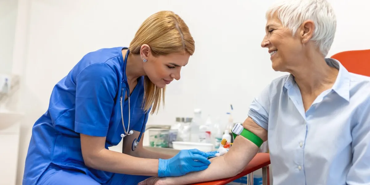 preparation for blood test with senior woman by female doctor medical uniform on the table in white bright room nurse pierces the patient's arm vein with needle blank tube