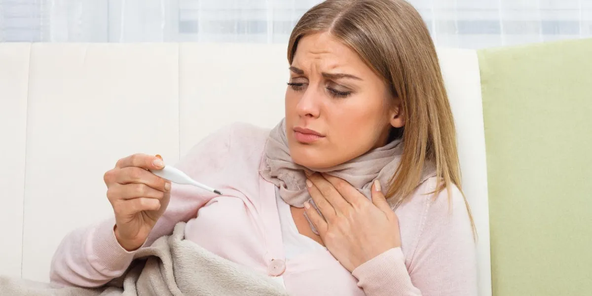 young woman is having sore throat and she is checking temperature