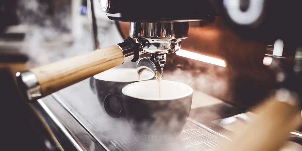 espresso poruing from coffee machine at cafe