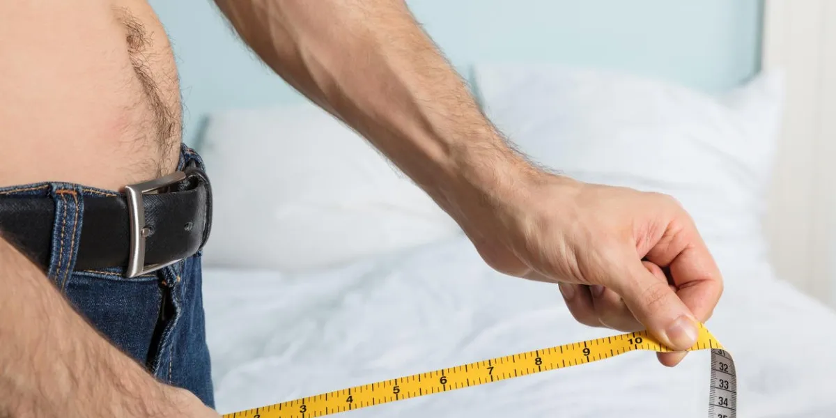 close-up of a man using measuring tape on jean at home