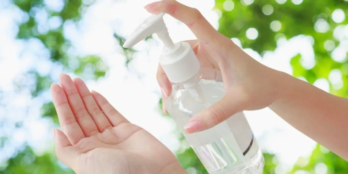 femelle, utilisation, main, presse, bouteille, et, verser, désinfectant à base d'alcool, sur, les autres mains, appliquer, tous, sentier, corps, nature verte, bokeh, fond