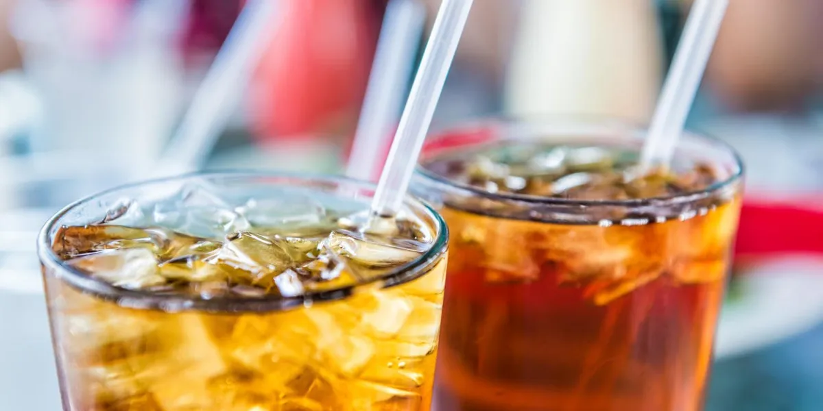 macro closeup of iced tea or soda with ice cubes and straw in glass