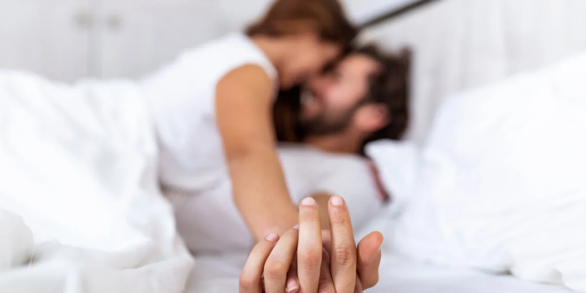romantic couple in bed enjoying sensual foreplay focus on hands man and woman happy sensual young couple lying in bed together beautiful loving couple kissing in bed
