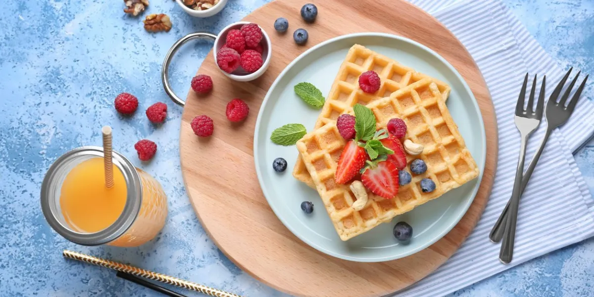 composition with delicious waffles and berries on color background