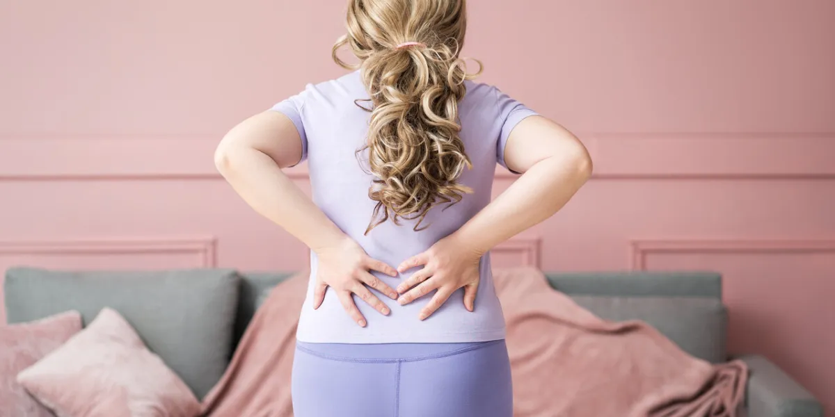 back pain, kidney inflammation, woman suffering from backache at home, health problems concept on pink background