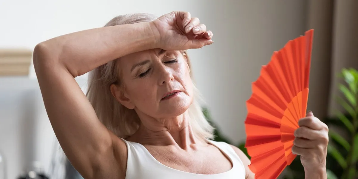 tired overheated middle aged lady wave fan suffer from menopause exhaustion complain on heat at home, stressed old woman sweat feel uncomfortable hot in summer weather problem without air conditioner