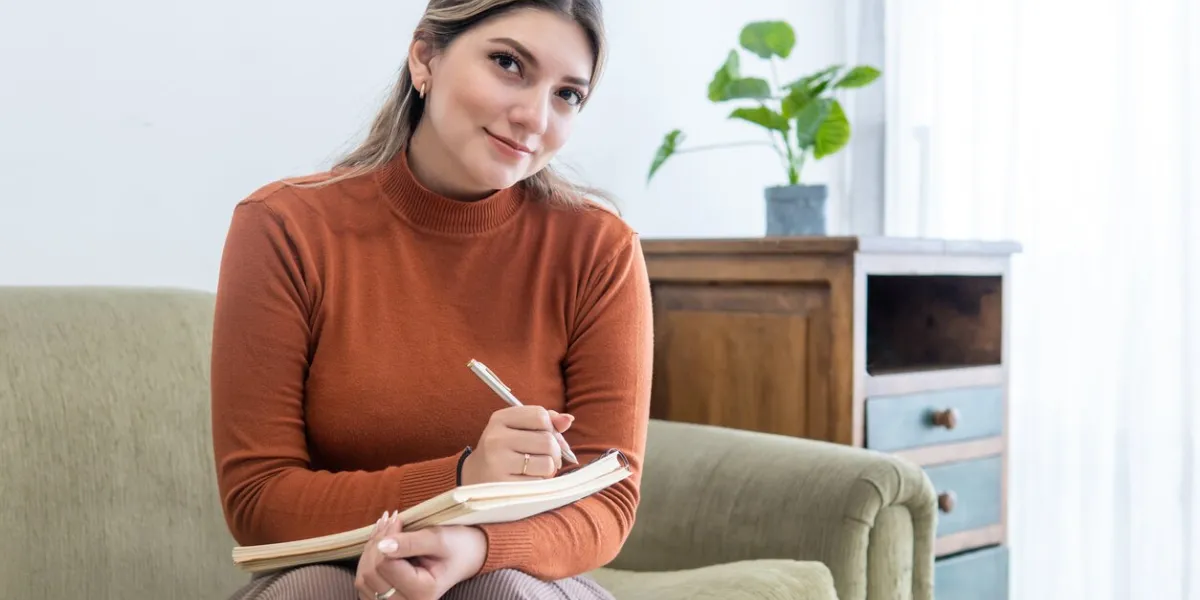young female psychologist looking at camera with her notebook and a pen in her office