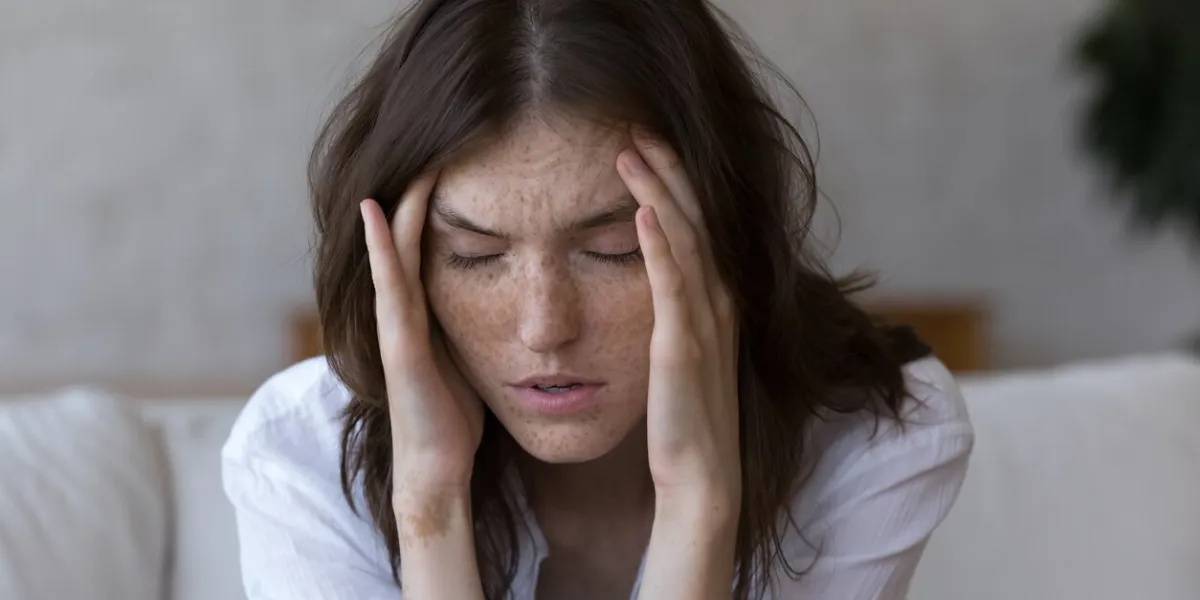 young freckled woman closed eyes, touches her temples suffers from severe headache feels unhealthy, close up face shot life troubles, panic attack, painful sensations, chronic migraine hurt concept