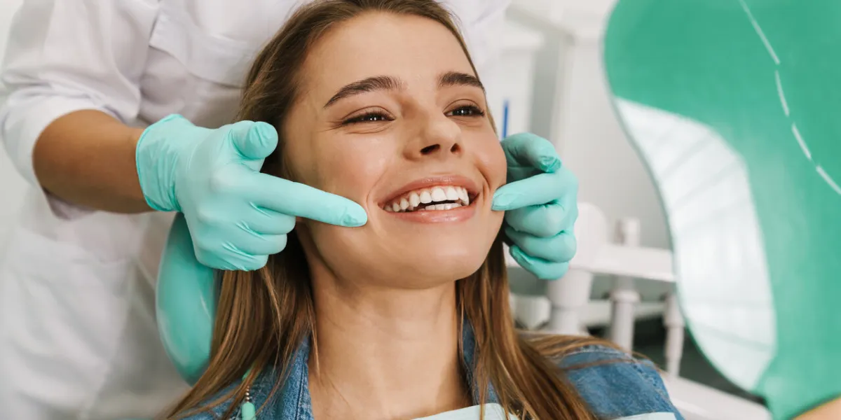 european young woman smiling while looking at mirror in dental clinic