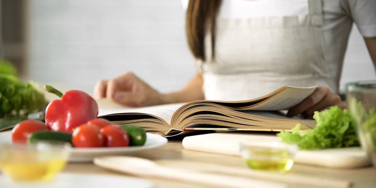 housewife reading cooking book with fresh vegetables and kitchen tools on table, stock footage