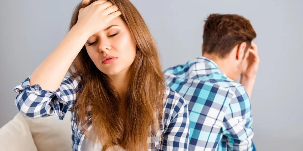 portrait of young sad woman with headache after quarrel sitting back to her husband