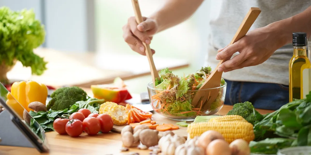 vegetarian man mixing vegetable salad in bowl