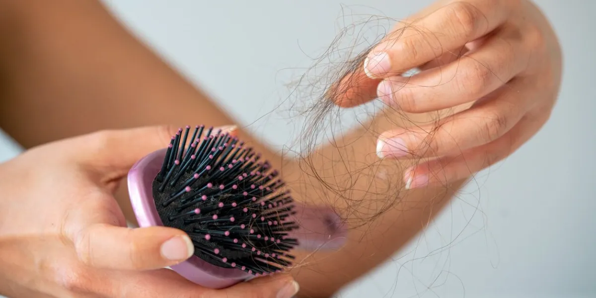 woman losing hair on hairbrush in hand on bathroom background stock photo