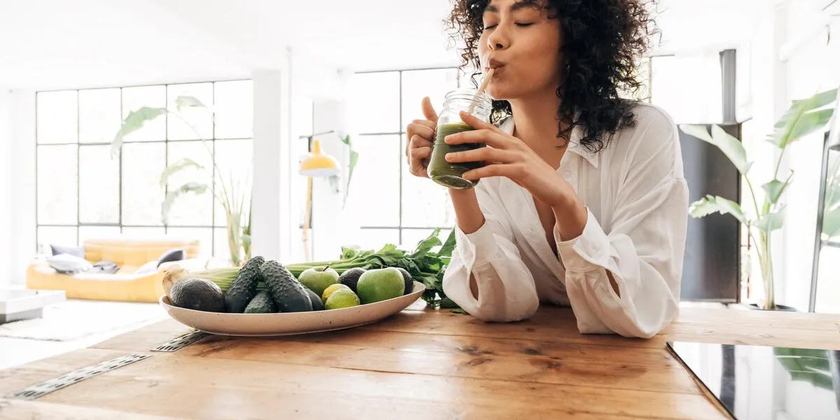 young african american woman drinking green juice with reusable bamboo straw in loft apartment home concept healthy lifestyle concept copy space