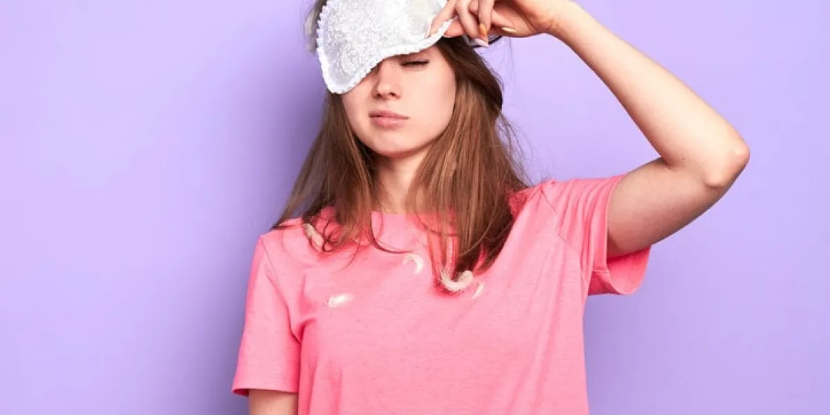 front view of exhausted young woman raises slightly her eye mask, trying to open sleepy eyes, needs more rest after hard week, out of energy, hates morning sleep and wake up concept