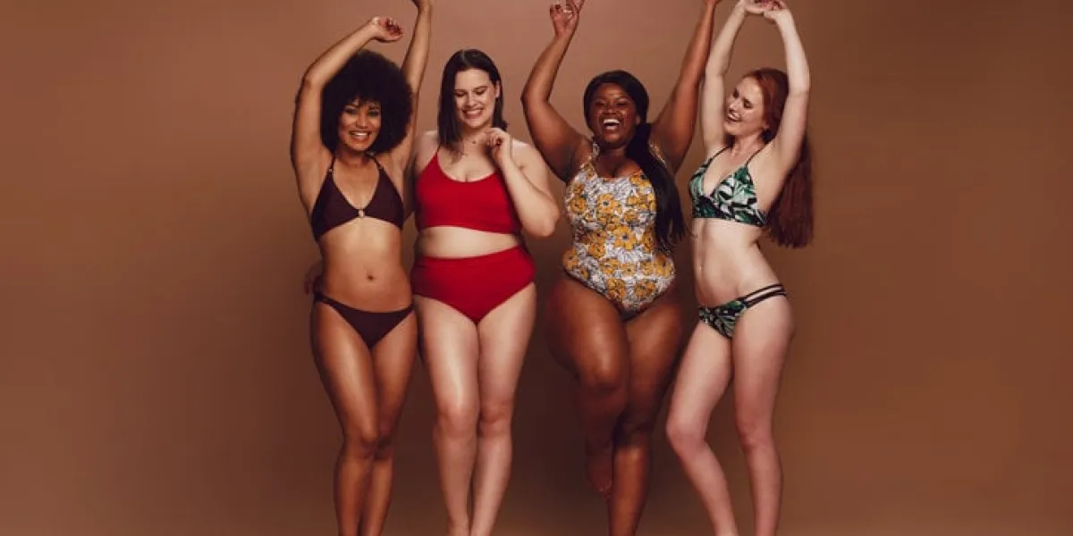 full length of different size women in bikinis dancing together over brown background multi-ethnic women in swimwear enjoying themselves