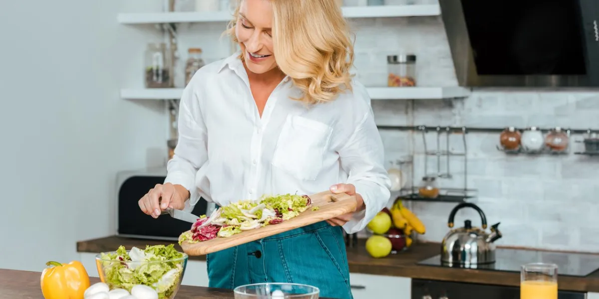 beautiful adult woman making healthy salad at kitchen
