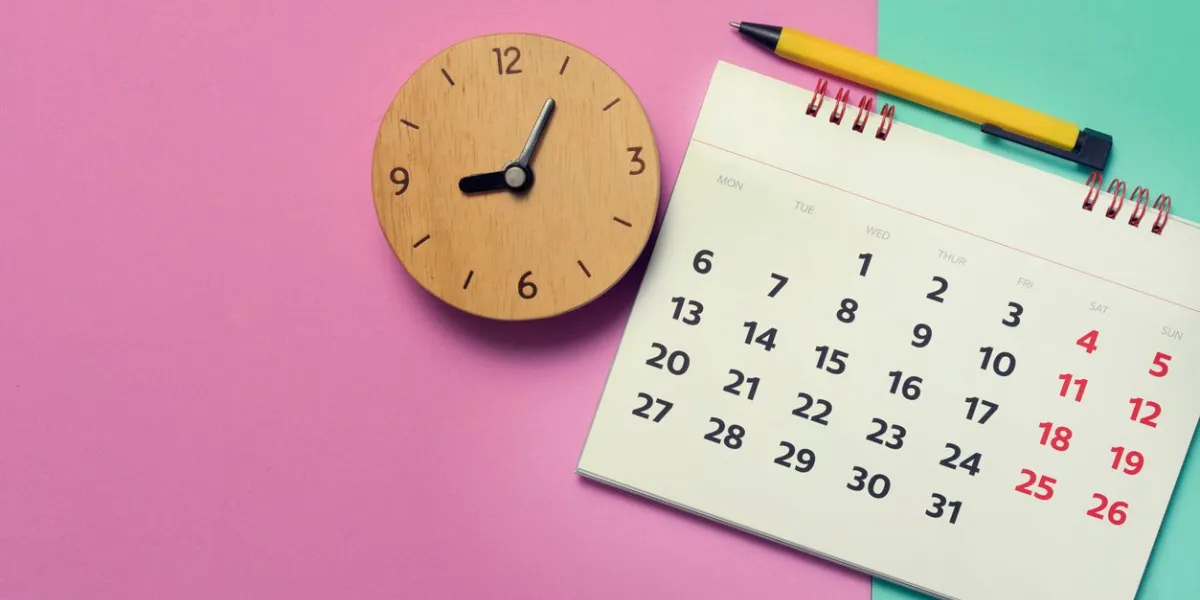 close up of calendar and clock on pink and green the table, planning for business meeting or travel planning concept